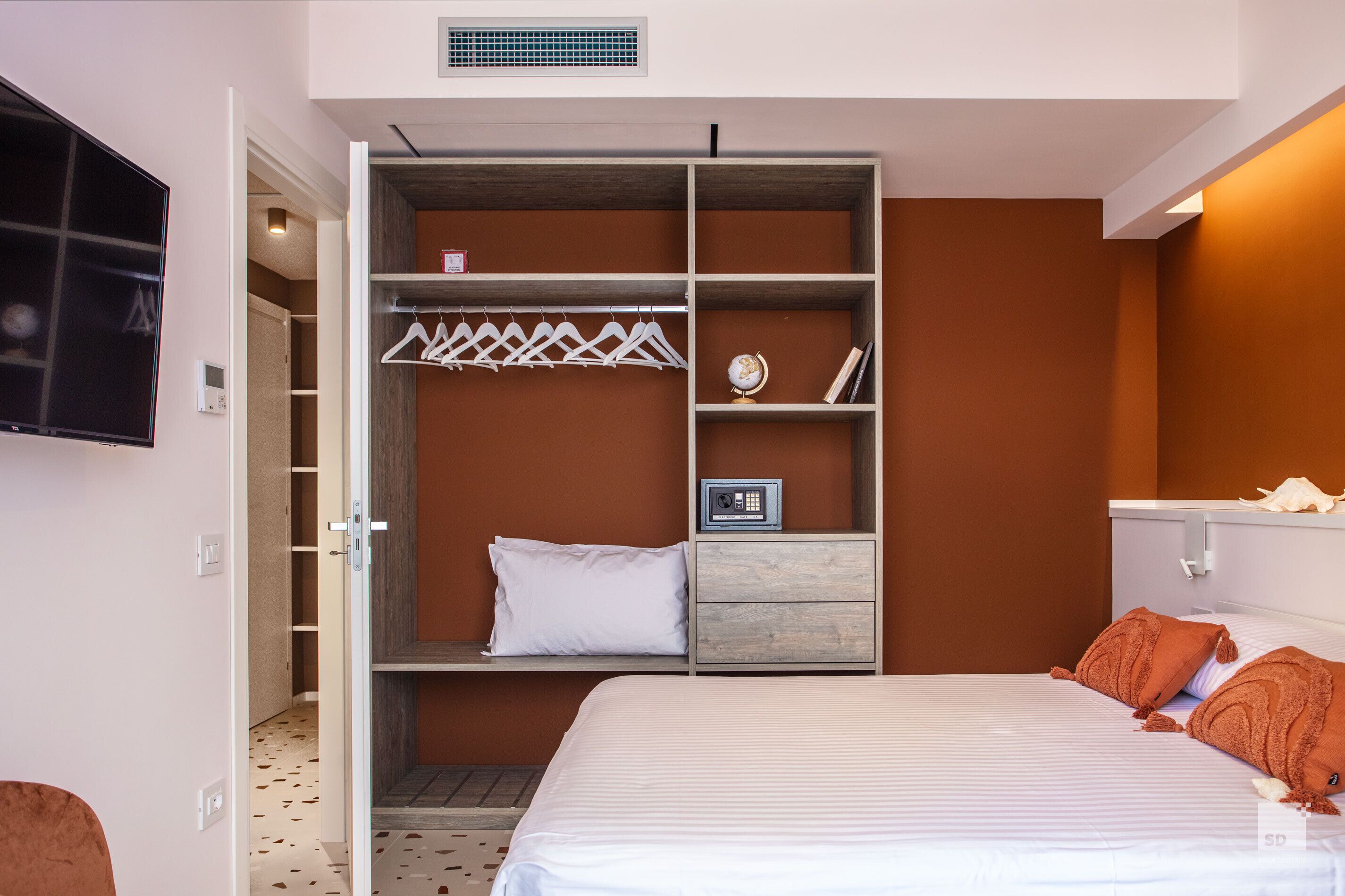 Un dormitorio con cama, armario, televisor y mesita de noche.
