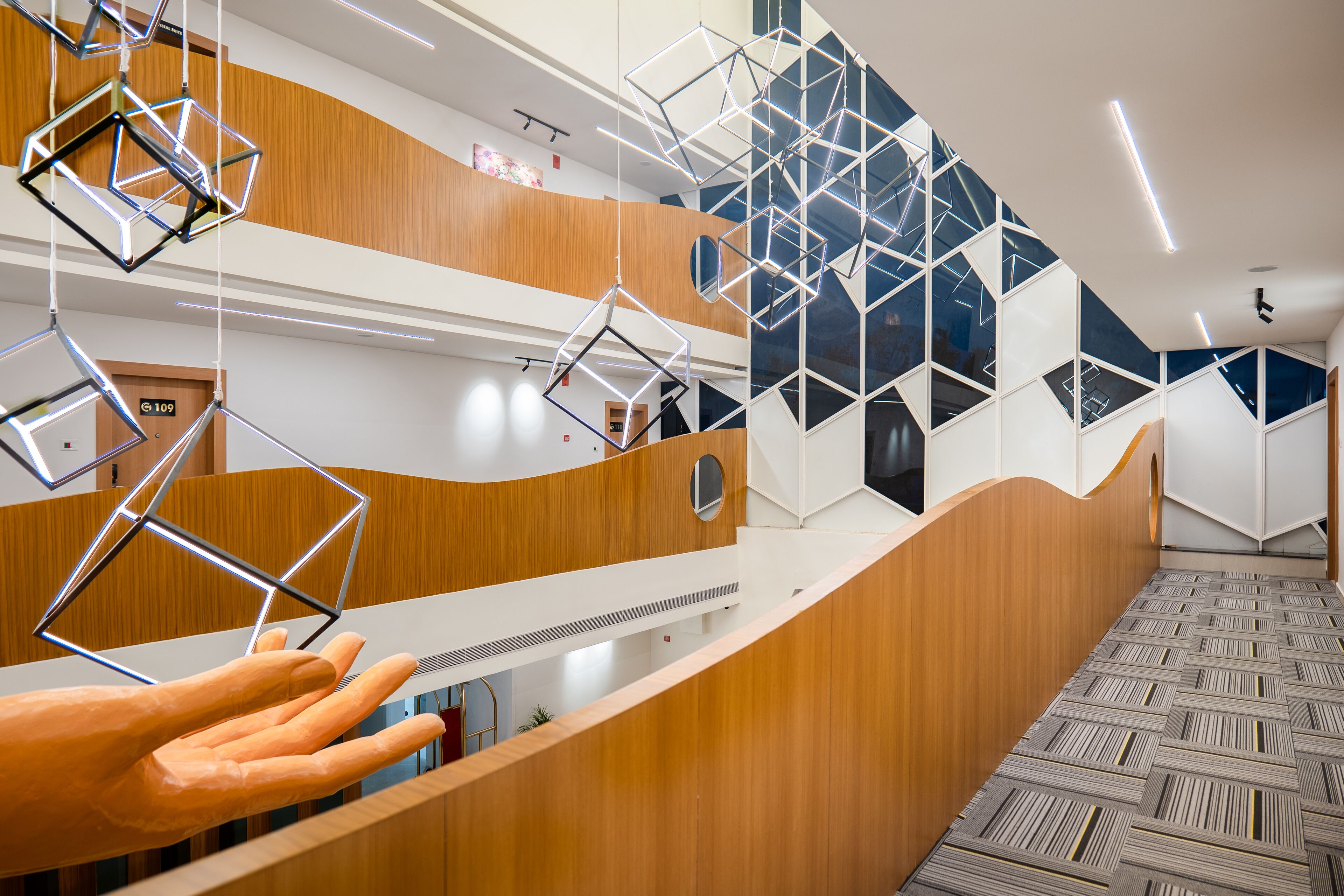 Un intérieur moderne avec des luminaires aux formes géométriques, des lambris en bois et un tapis à motifs.