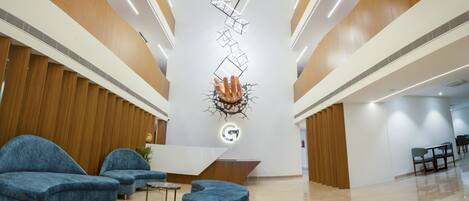 A modern lobby with a reception desk, blue seating, and a unique ceiling design.
