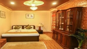 A bedroom with a bed, a nightstand, a lamp, a wooden cabinet, and a chandelier. - MeroStay 139 Hotel Mandala (Kathmandu)