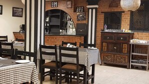A restaurant with checkered tablecloths, wooden chairs, and a brick wall. - MeroStay 139 Hotel Mandala (Kathmandu)