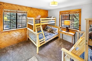 A bunk bed with a desk and lamp, wooden walls, and large windows. - Bear Mountain Log Lodge By Destination Big Bear: Walking distance to Bear Mountain,Golf Course and Hiking Trails! Hot Tub! Fenced Yard! Pet Friendly! (Big Bear Lake)