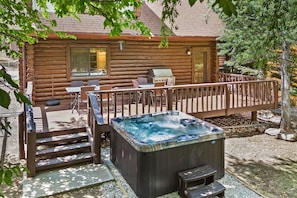 A log cabin with a hot tub, outdoor seating, and a deck.