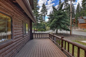 Eine Blockhütte mit einer Holzterrasse und Blick auf einen Wald.