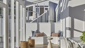 A modern outdoor seating area with a white railing, a small table, and wicker baskets. - The Cape Retreat with stunning views (Cape Schanck)