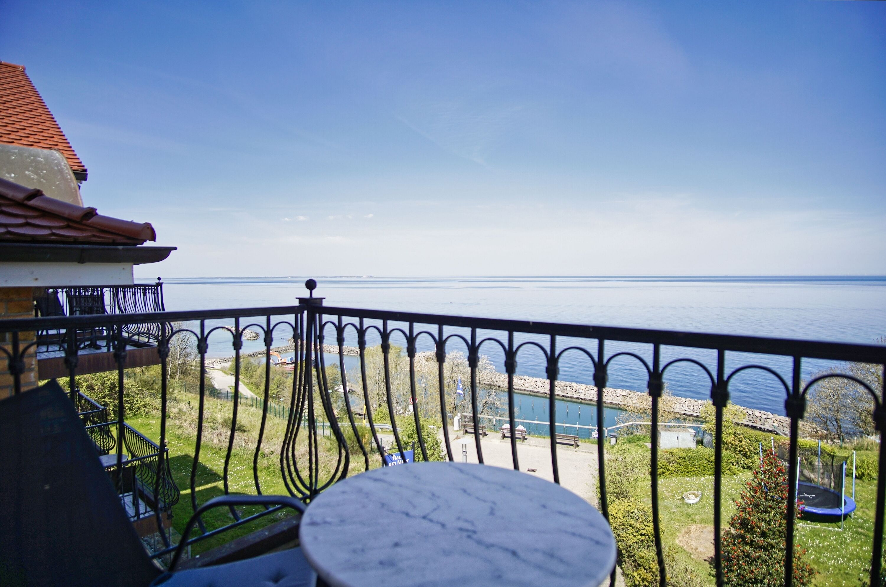 A balcony with a view of the sea, a table, and a railing.