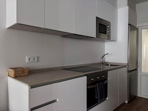 A modern kitchen with white cabinetry, a built-in microwave, a stainless steel sink, and a double oven.
