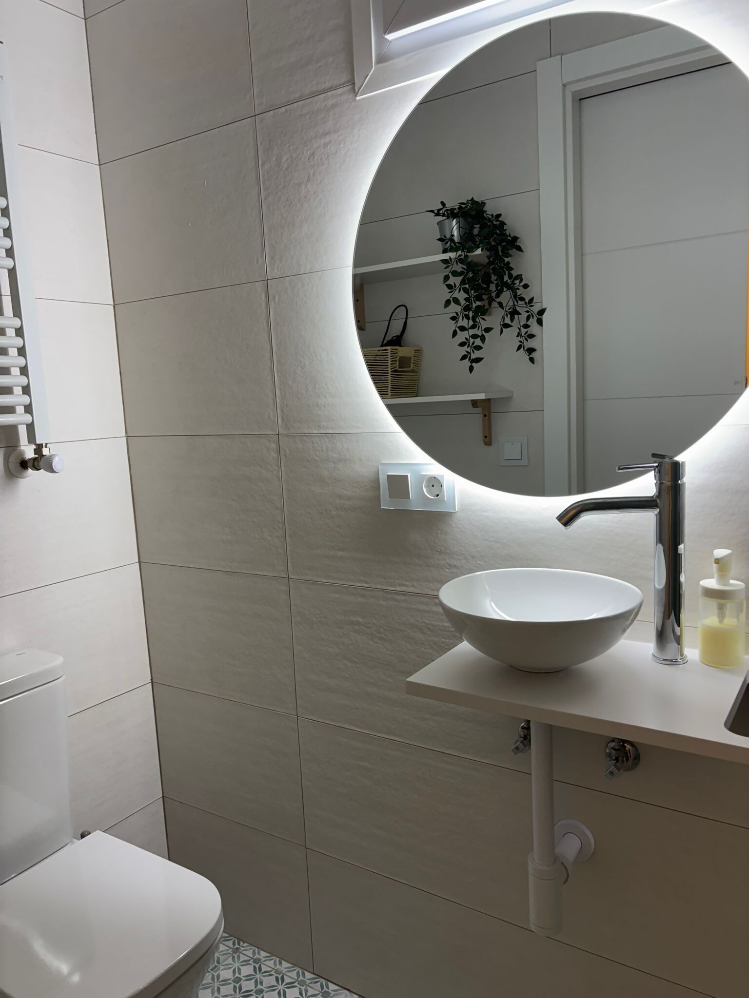 Un baño con un espejo redondo, un lavabo blanco y un inodoro.