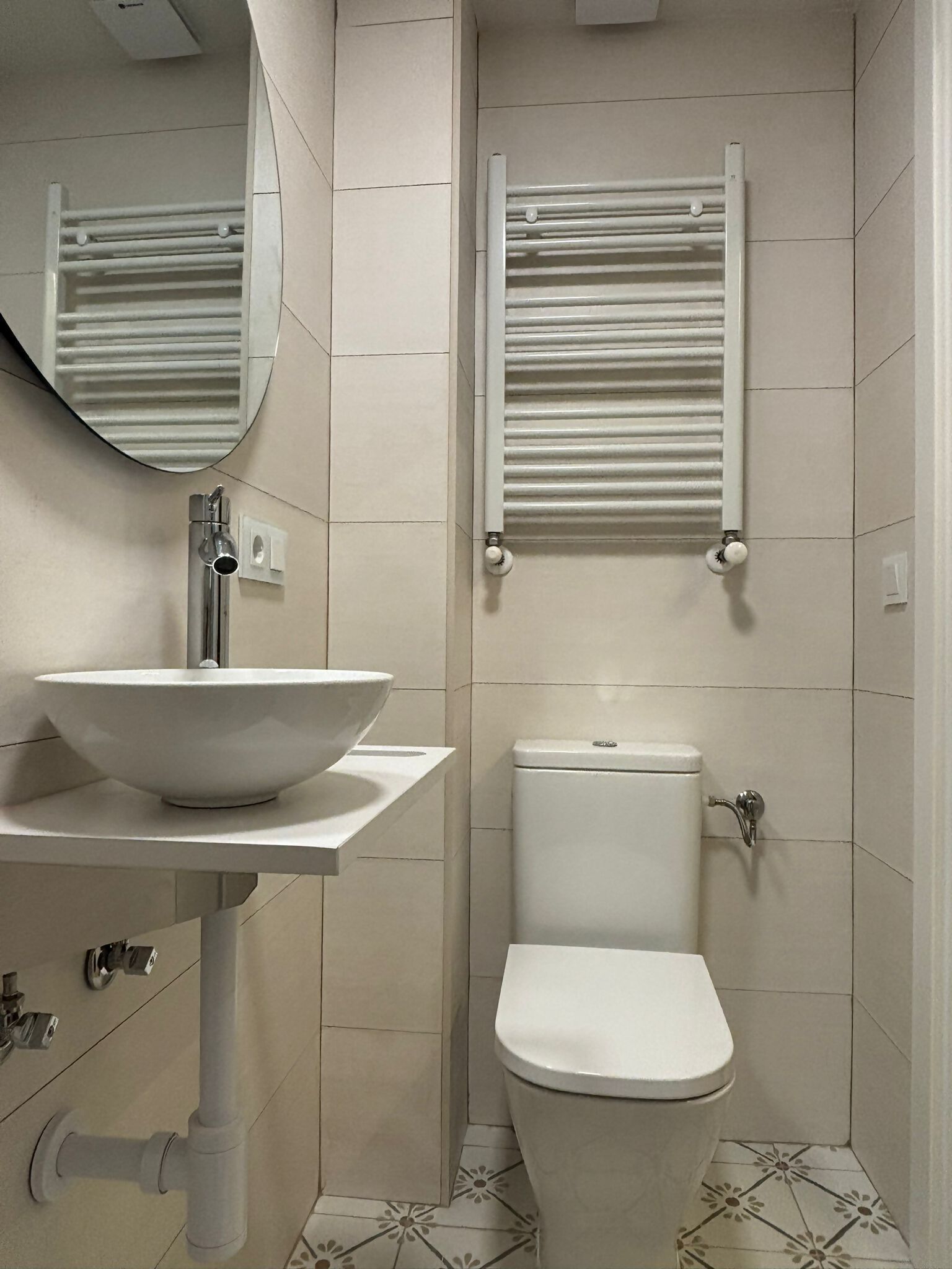 Et badeværelse med hvid vask, toilet og håndklædestige.