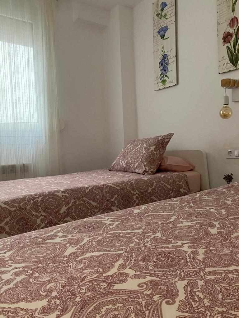 Un dormitorio con dos camas, cada una con ropa de cama estampada, una mesita de noche y una lámpara de pared.