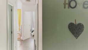 A hallway with a door leading to a room, a wall with the word "Home" and a heart-shaped decoration. - Apartamento en el Casco Antiguo de Pamplona - Ayla Camino de Santiago (Pamplona/Iruña)