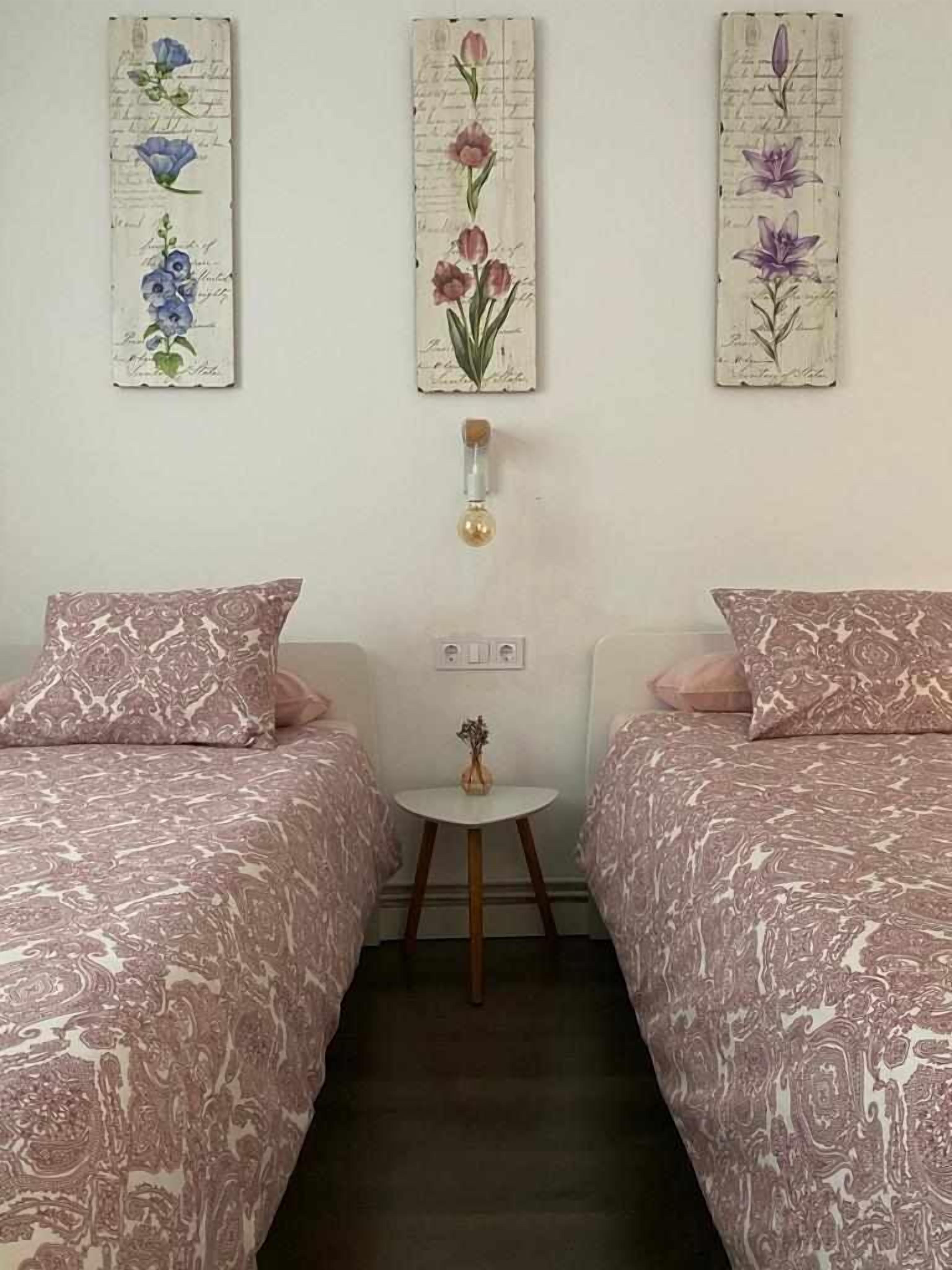 A room with two beds, a small table, and wall art.
