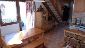 Une cuisine chaleureuse avec des meubles en bois, une table à manger avec des bancs, et un escalier menant à un étage supérieur.