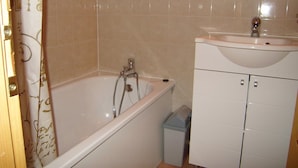 Une salle de bain avec une baignoire, un lavabo et un miroir au-dessus du lavabo.