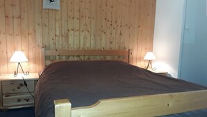 Un lit en bois avec une tête de lit, deux tables de chevet avec des lampes et un panneau fixé au mur.