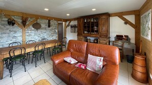 A cozy living room with a wooden dining table, leather sofa, and a stone wall. - Spacious 3-Bed Apt for 8, 80m from Cernix Slopes, Pet-Friendly, Terrace, Parking (Crest-Voland)