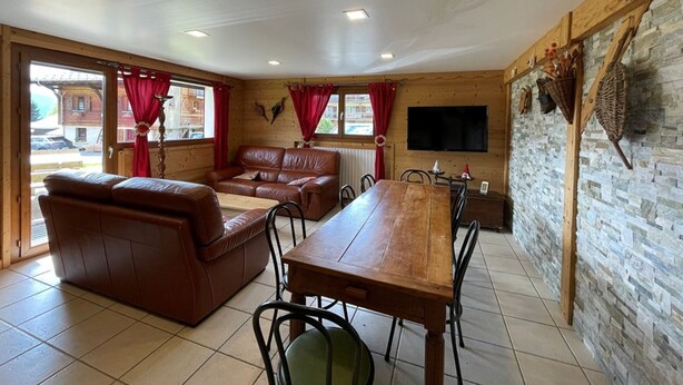 A cozy room with a wooden interior, a leather sofa, a dining table, and a stone wall. - Spacious 3-Bed Apt for 8, 80m from Cernix Slopes, Pet-Friendly, Terrace, Parking (Crest-Voland)