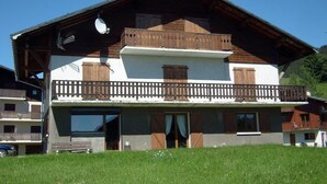 A two-story chalet with a balcony, wooden exterior, and a clear sky. - Spacious 3-Bed Apt for 8, 80m from Cernix Slopes, Pet-Friendly, Terrace, Parking (Crest-Voland)