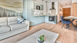 Una cocina moderna con armarios azul claro, horno empotrado y un comedor con mesa de madera y sillas azules.