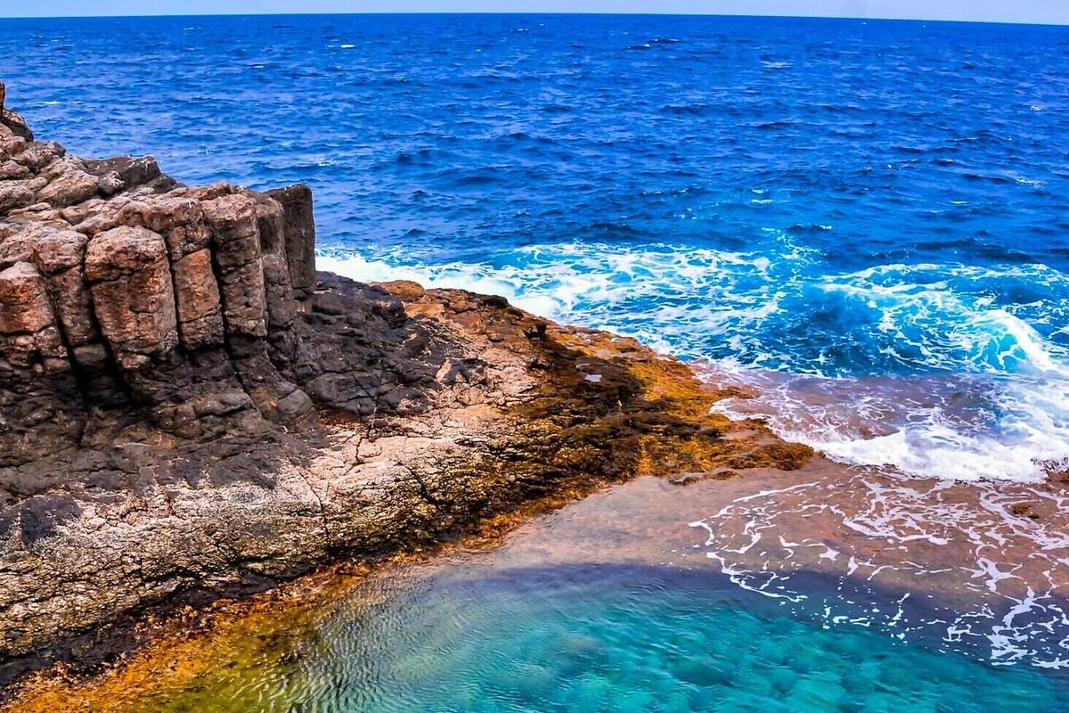 A coastal landscape with rocky formations and clear blue waters.