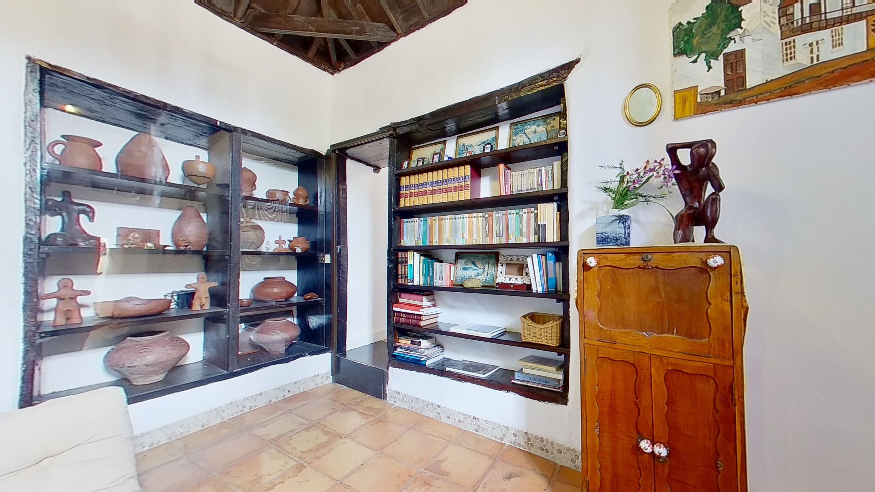A room with two open shelves displaying pottery and books.