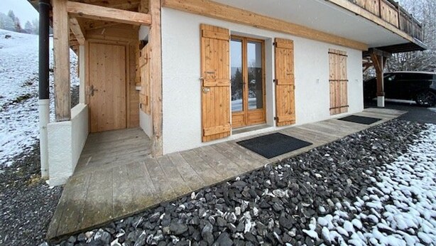A wooden chalet with a balcony and a covered entrance.