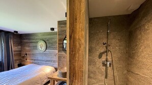 Une chambre moderne avec un mur en bois, un lit, une table de chevet, un miroir et un espace douche.