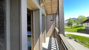 Un balcon en bois offrant une vue sur un paysage verdoyant et une route.