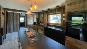 Une cuisine moderne avec des meubles en bois, un grand îlot central, des luminaires suspendus et un four encastré.