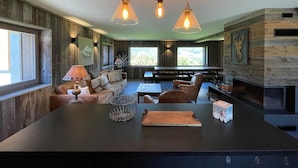 Une cuisine moderne dotée d’un îlot central, de luminaires suspendus et d’un mur en bois rustique.