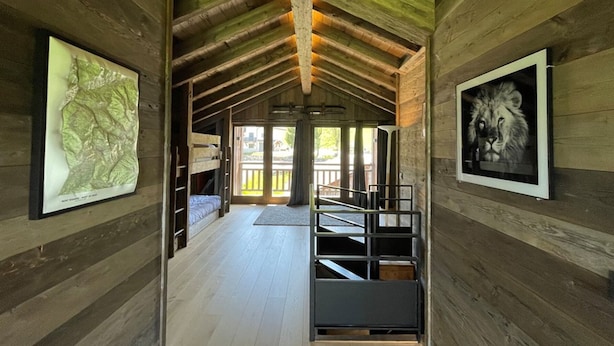 Un intérieur en bois avec des lits superposés, une carte encadrée et une image de lion.