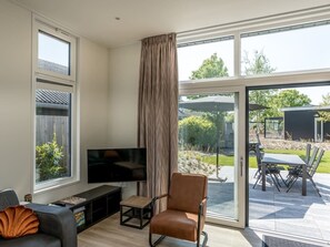 Ein modernes Wohnzimmer mit Flachbildfernseher, Ledersessel und Essbereich mit Tisch und Stühlen.