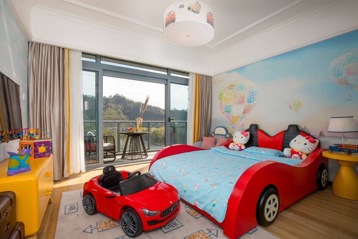 A child's bedroom with a large bed, a toy car, and a Hello Kitty bedspread.
