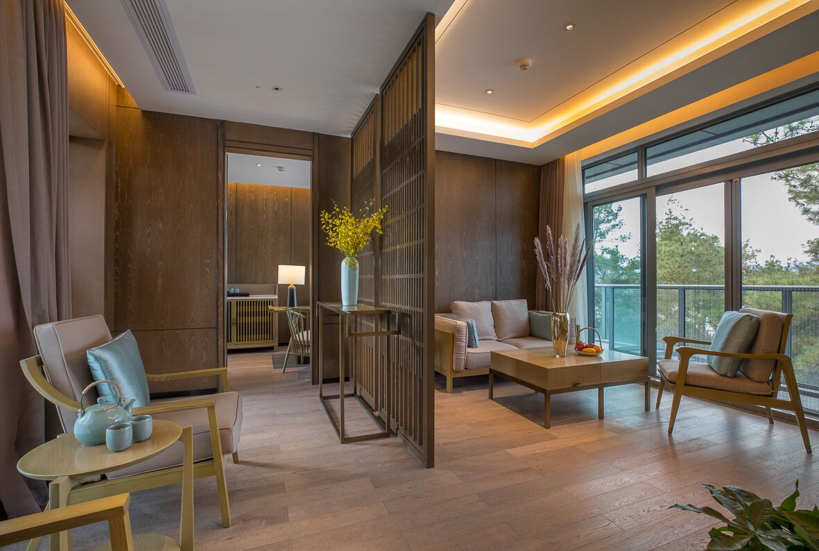 Ein modernes Hotelzimmer mit Holzboden, einer Couch, einem Couchtisch und Blick ins Freie.