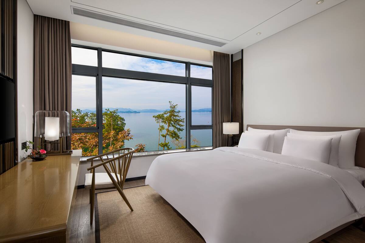 A hotel room with a large bed, a desk, and a view of the water.