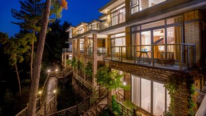A multi-story building with large windows, a wooden deck, and a staircase leading to a balcony. - Bright QiandaoLake Resort (Hangzhou)