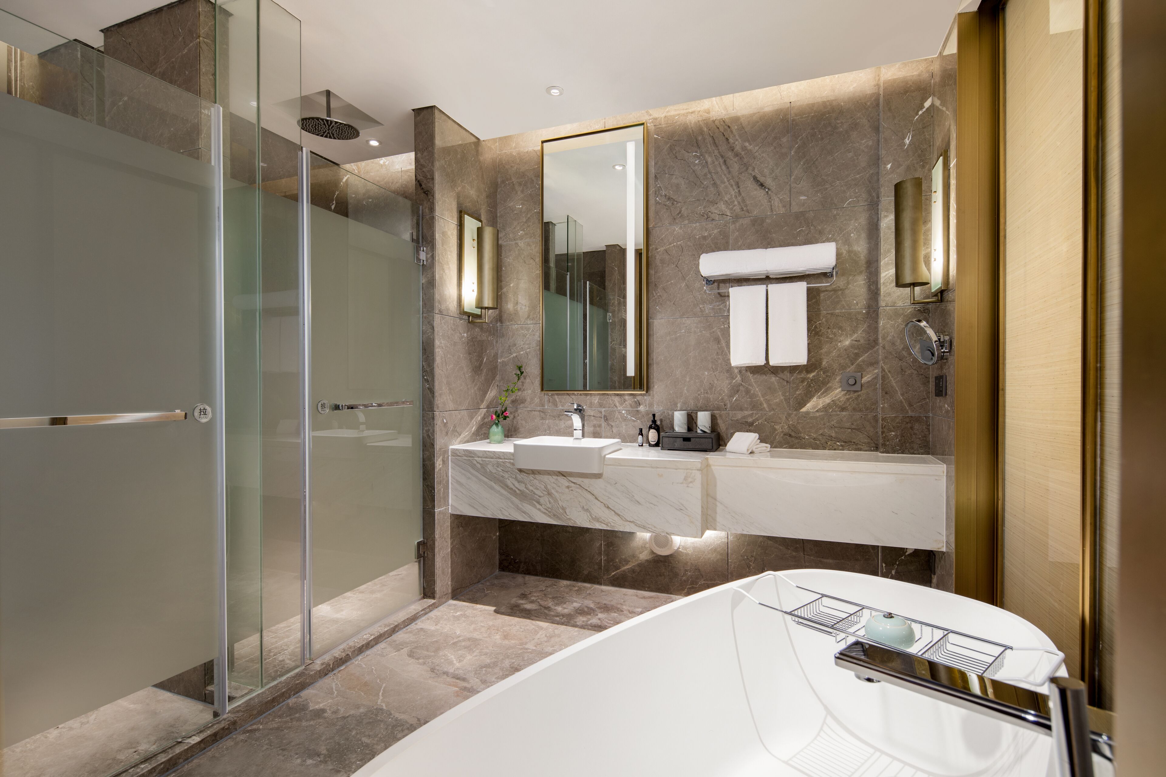 A modern bathroom with a glass-enclosed shower, a large mirror, a white sink, and a freestanding bathtub.