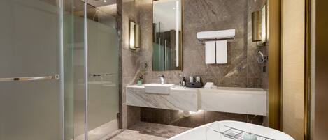 A modern bathroom with a glass-enclosed shower, a large mirror, a white sink, and a freestanding bathtub.
