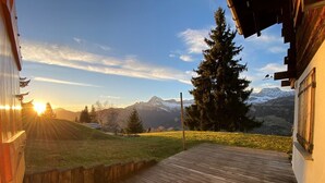 Eine Holterrasse mit Blick auf ein Gebirge und einen Sonnenuntergang.