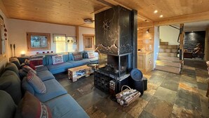 Ein gemütliches Wohnzimmer mit Kamin, Holzboden und einer Treppe, die zu einer anderen Ebene führt.