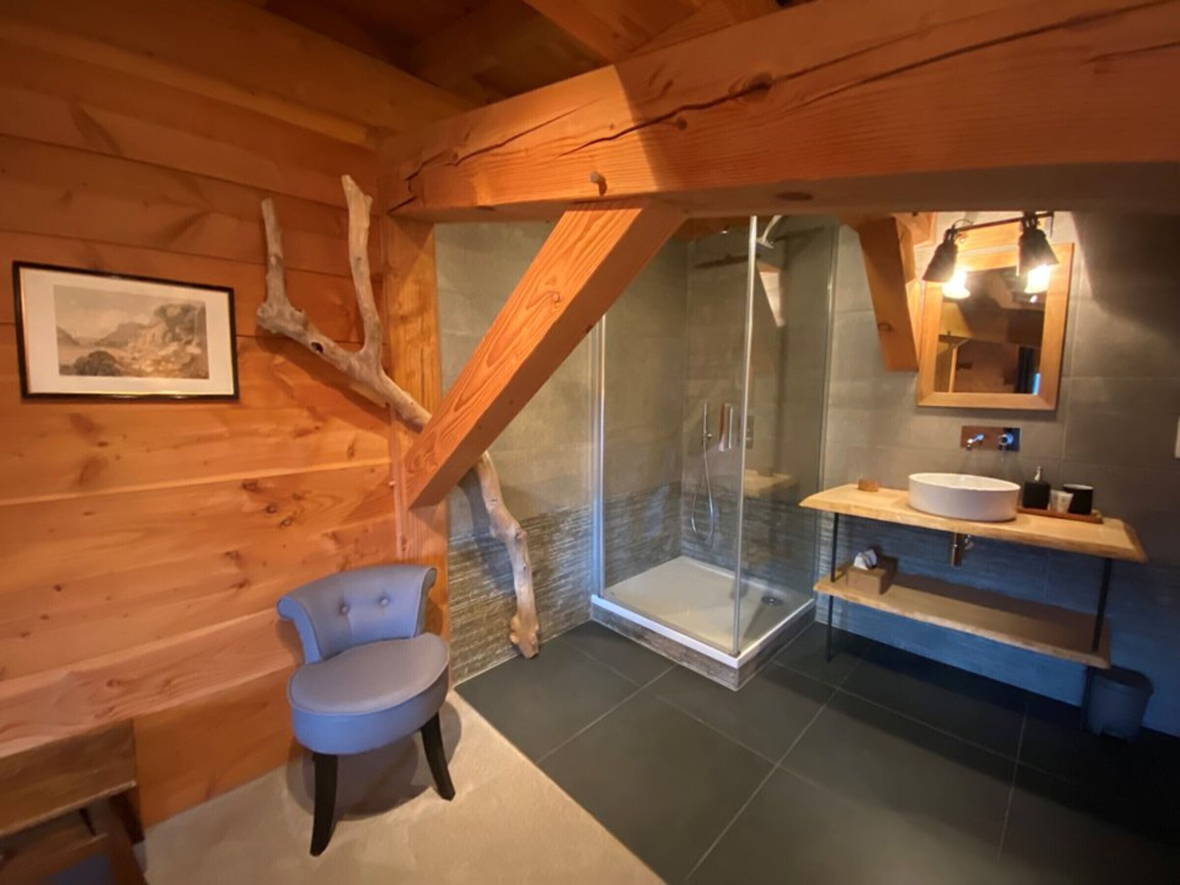 Un intérieur en bois avec une douche fermée par des parois de verre, un lavabo et une chaise.