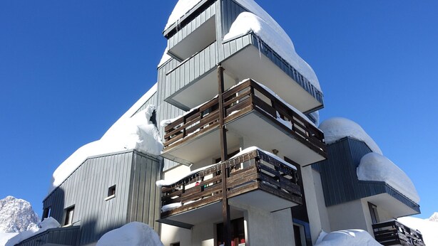 Un hotel a più piani con balconi e paesaggi innevati.