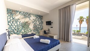 Un dormitorio con cama, escritorio y vista al mar.