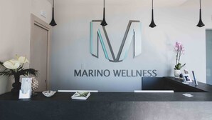 Un mostrador de recepción con el logotipo de Marino Wellness, un florero con flores y un pequeño cuenco.