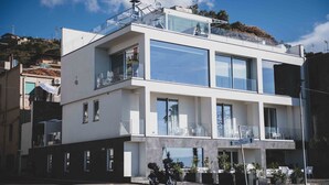 Un edificio moderno de dos pisos con ventanas amplias, balcones y asientos al aire libre.