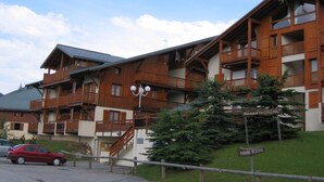 A multi-story wooden building with balconies and a sign indicating a parking reserve. - Cozy 1-Bedroom Apartment, Well-Equipped, Near Ski Slopes and Village Center (Crest-Voland)
