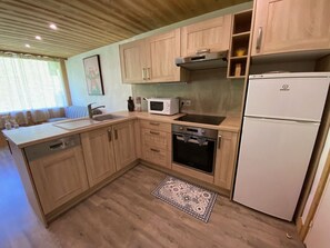 Una cocina compacta con armarios de madera, un microondas, un horno y un refrigerador.