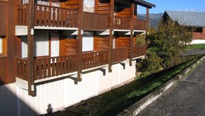 Una cabaña de madera con balcones, paredes exteriores blancas y una vista despejada del paisaje circundante.
