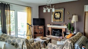 Un salon avec une cheminée, un téléviseur et un télescope.