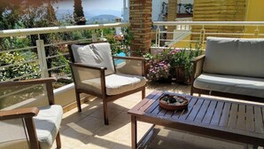 Une terrasse avec une table en bois, deux chaises et un canapé.